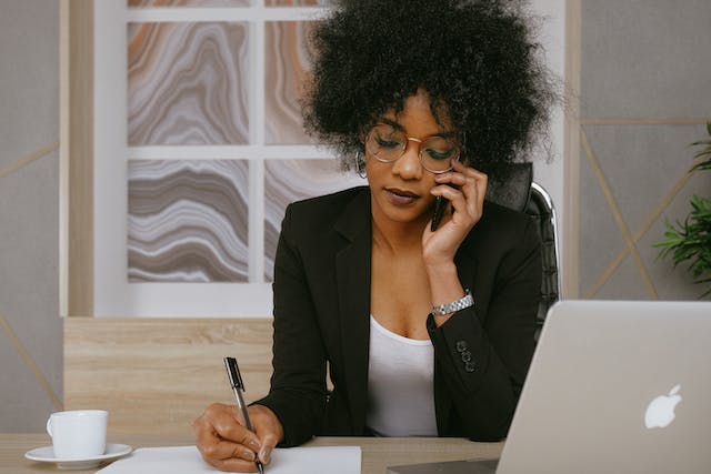 A person on a phone call and writing.