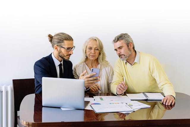 older couple meeting with a professional, with a laptop in front of them going over documents