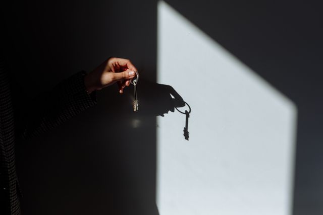 a person holding a key up in front of a wall